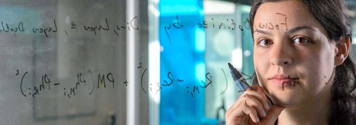 Dr. Agnes Cseh schreibt mathemathische Formeln an eine Glastafel